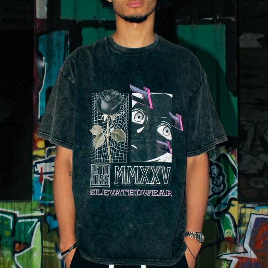 Person wearing a black t-shirt with graphic design and black pants with white drawstrings, standing in front of a graffiti-covered wall.